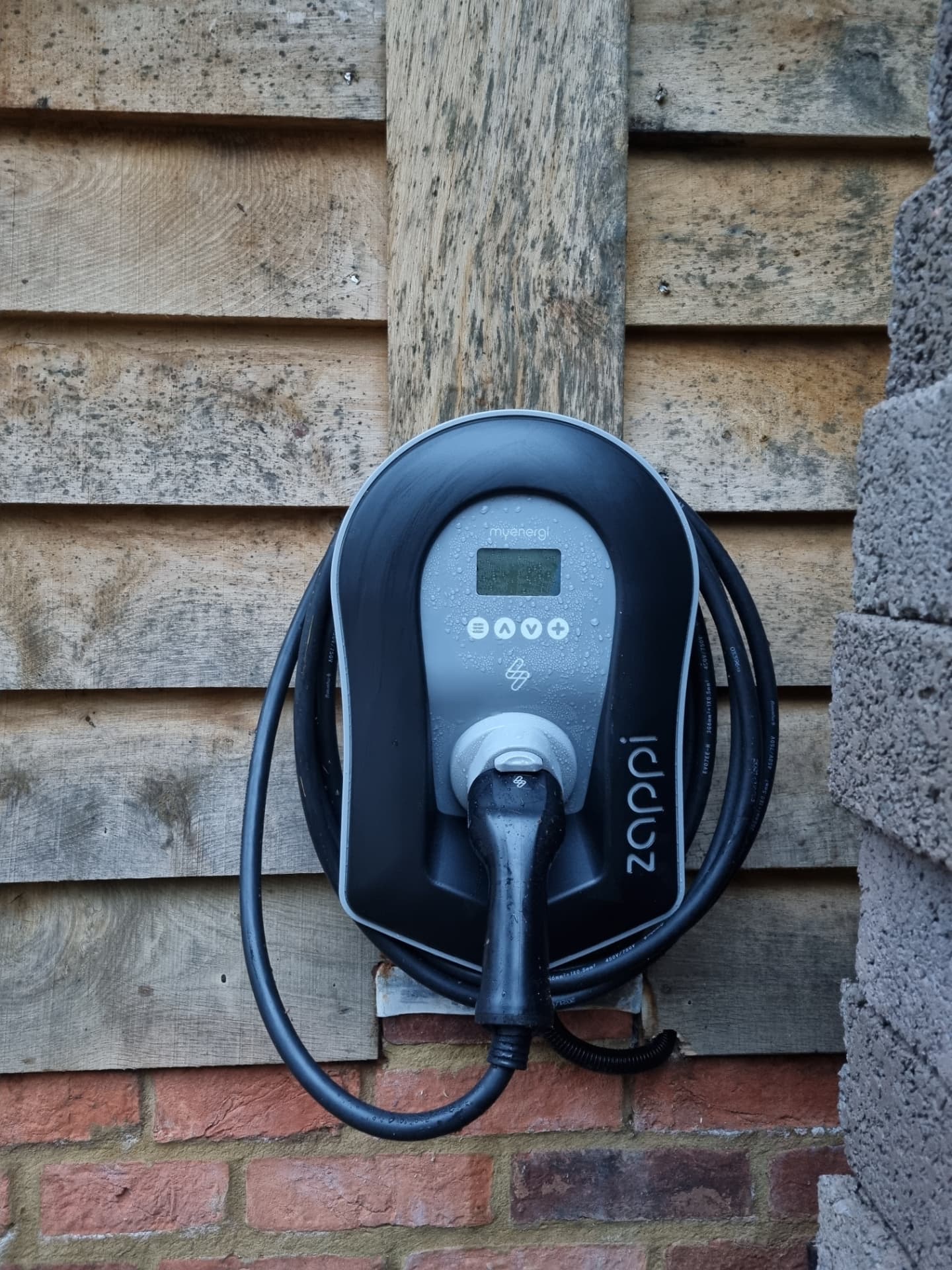 Zappi EV charger installed on a timber clad wall