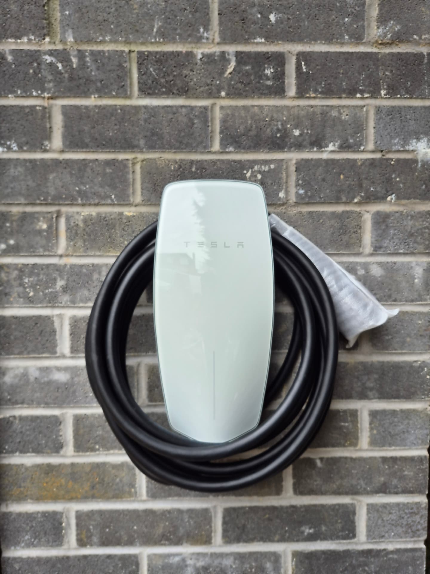 Tesla wall connector installed on a grey brick wall